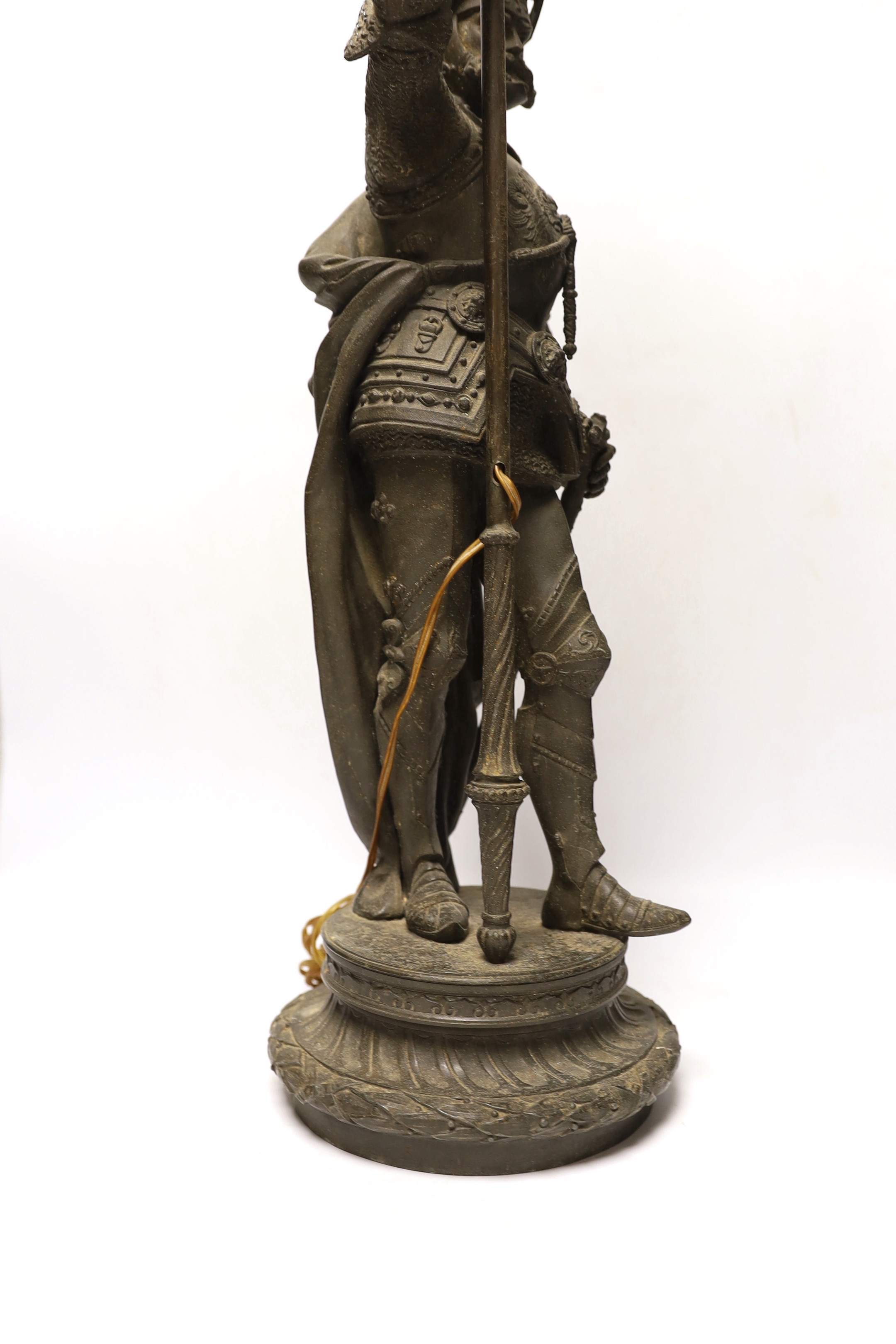 A spelter table lamp of a knight in armour carrying torch, with flame glass shade, approx 75cm high
